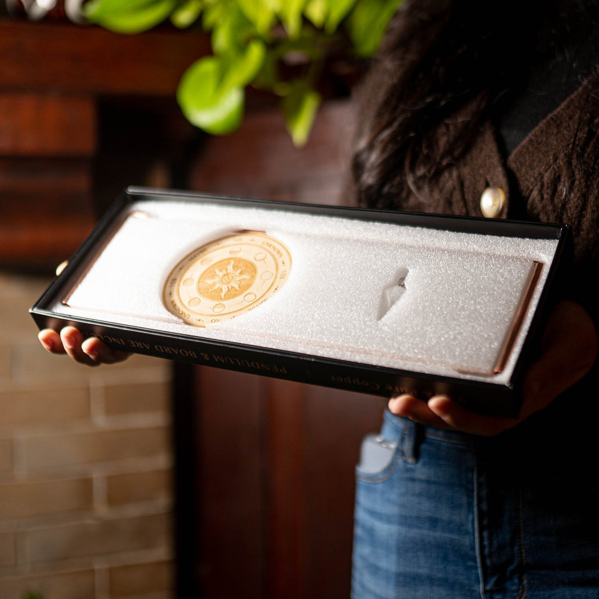 The Paranormic Dowsing Rods Kit in its open gift box, held in both hands.