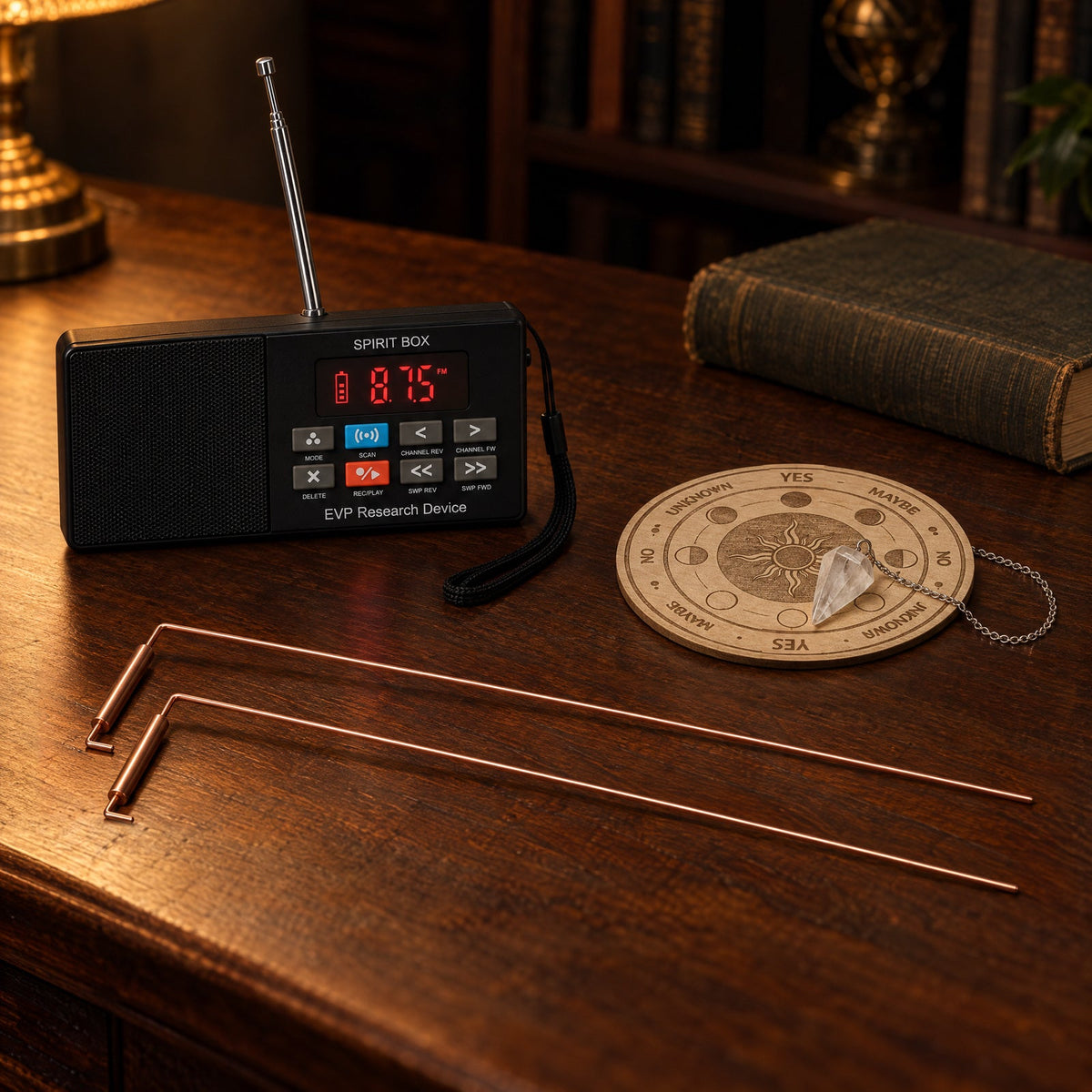 The Paranormic Spirit Box on a walnut desk beside two copper dowsing rods and the small wooden answer board with its quartz pendulum.