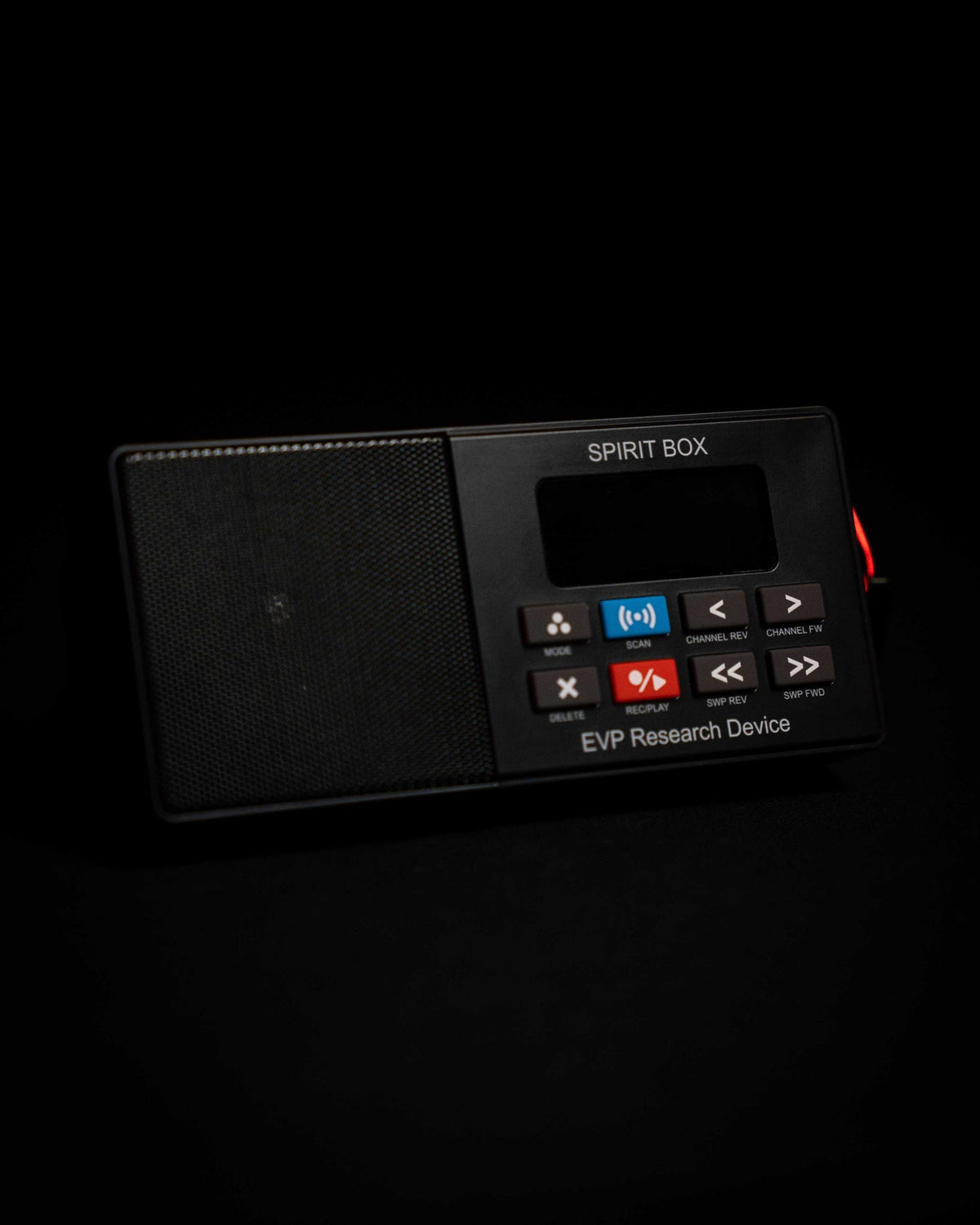The Paranormic Spirit Box on a black studio surface, showing its speaker grille, display and eight labelled buttons.